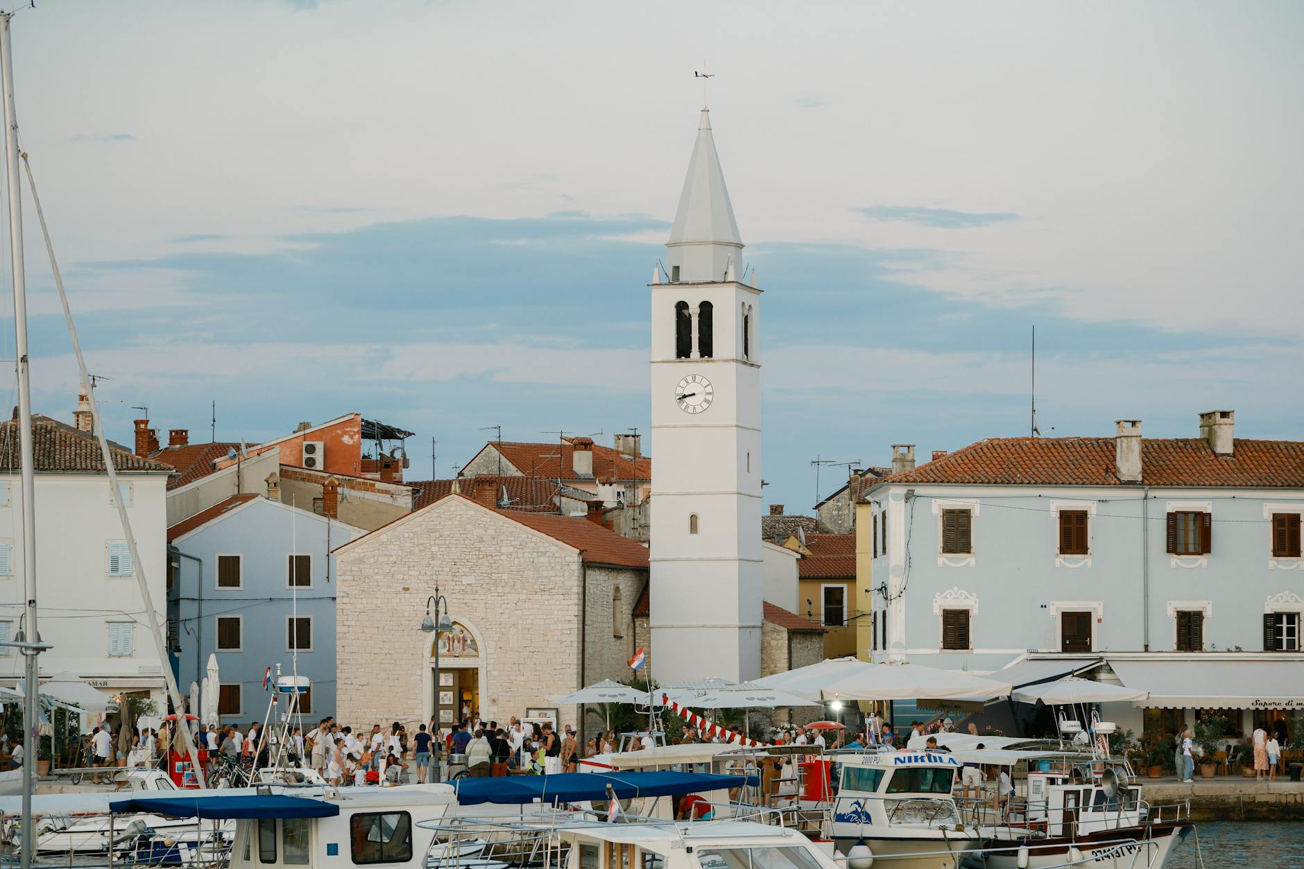 Chorwacki port o zmierzchu z łodziami i wieżą zegarową nad zatoką