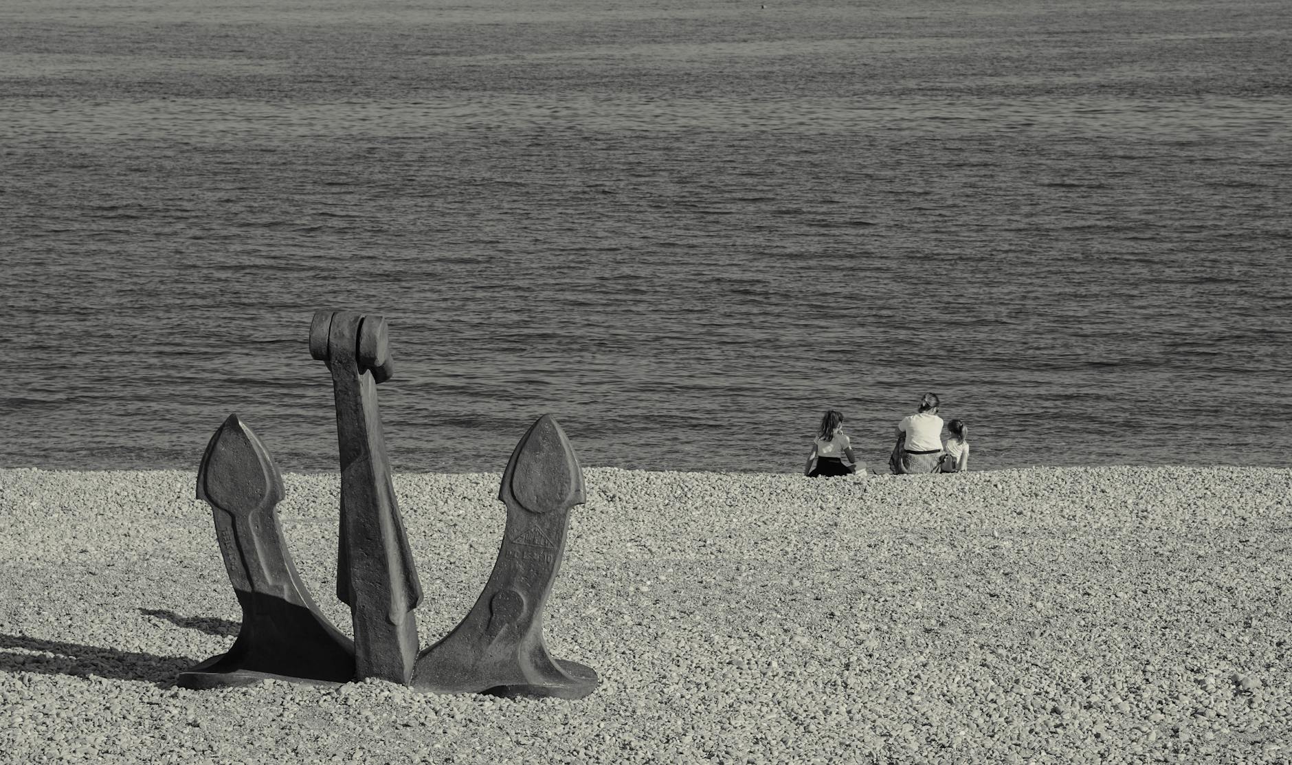 Rodzina na kamienistej plaży w Chorwacji obok dużej kotwicy