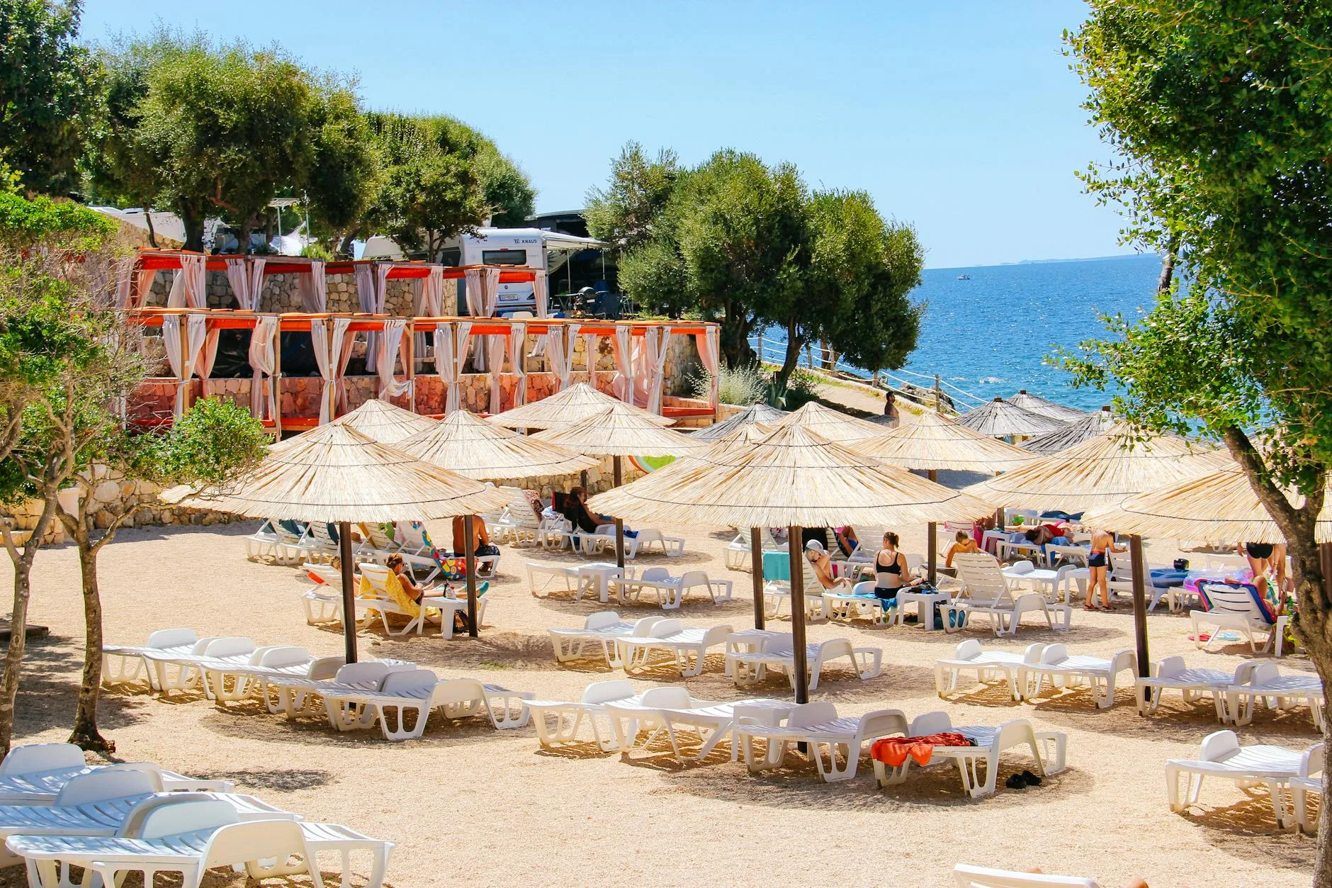 Chorwacja a odpowiedzialne podróżowanie: czy nasze wakacje mają sens? Plażowe leżaki i parasole w Novalji nad morzem w słoneczny dzień