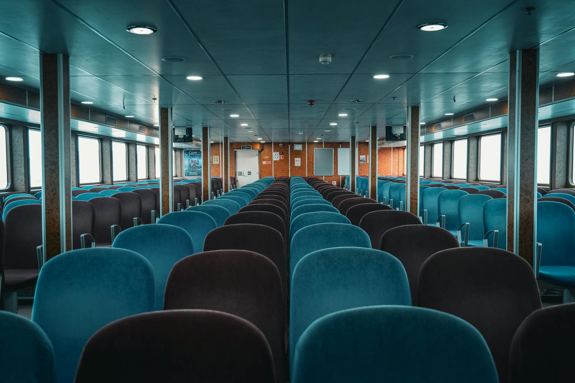 Jak planować rezerwacje promów i biletów wstępu do parków narodowych w szczycie sezonu Puste wnętrze nowoczesnego promu pasażerskiego z rzędami turkusowych foteli