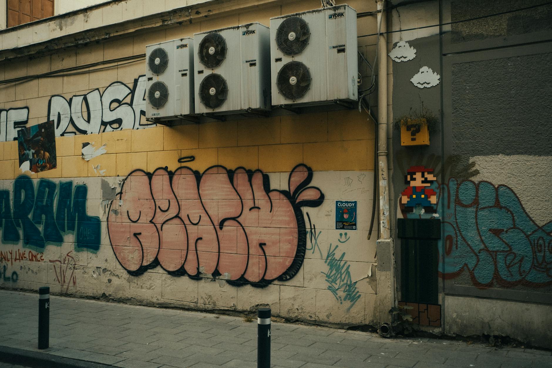 Kolorowe graffiti z pikselowym Mario na miejskiej ścianie z klimatyzatorami