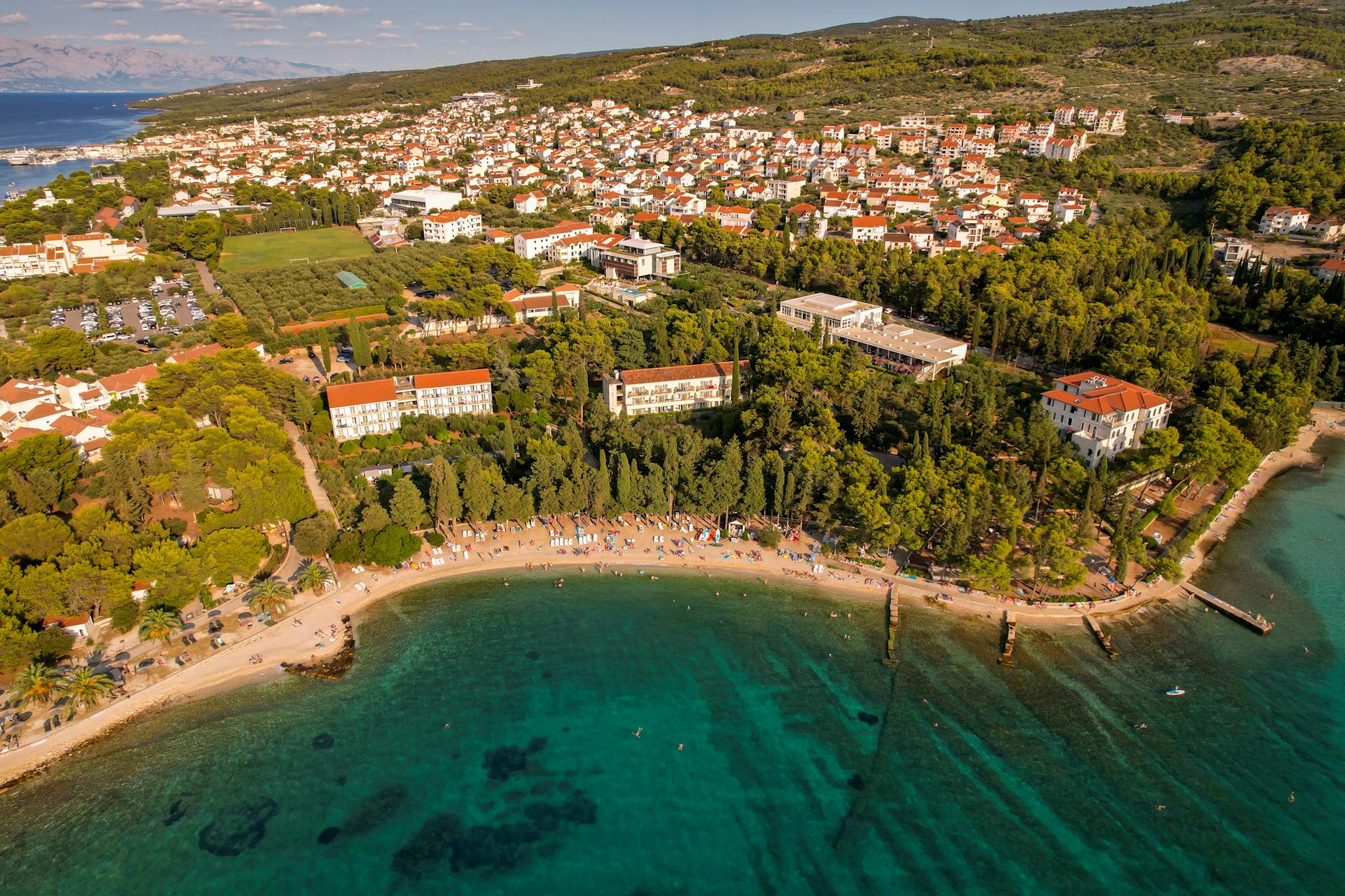 Nadmorskie miasteczko w Chorwacji z plażą i zielonym wzgórzem widziane z góry