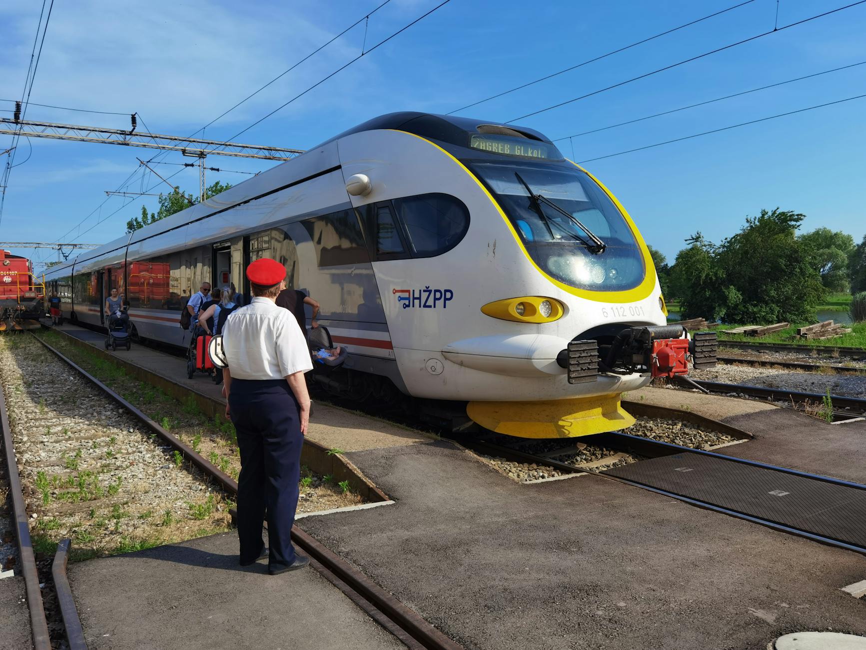 Nowoczesny pociąg na peronie, pasażerowie wsiadają, konduktor nadzoruje